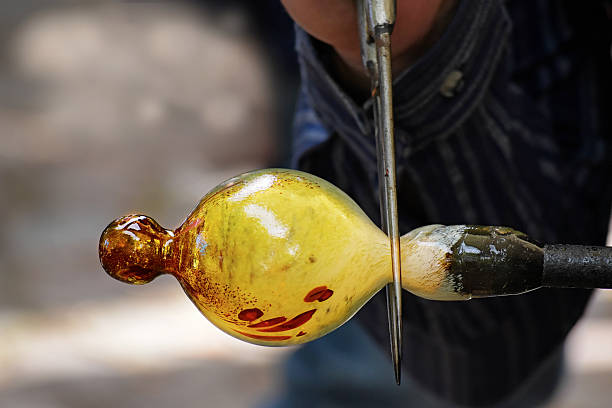 Manufacturing glass,  the traditional glassblower working on a handmade christmas bauble of melted glass on a rod, selected focus and narrow depth of field