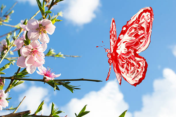 Red and white butterfly flying around pink peach blossom