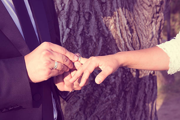 istock groom and the bride wearing a wedding ring 612254802