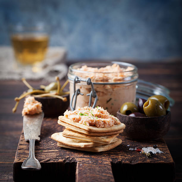 Smoked salmon and soft cheese spread, mousse Smoked salmon and soft cheese spread, mousse, pate in a jar with crackers, olives and capers on a wooden background tuna pate stock pictures, royalty-free photos & images