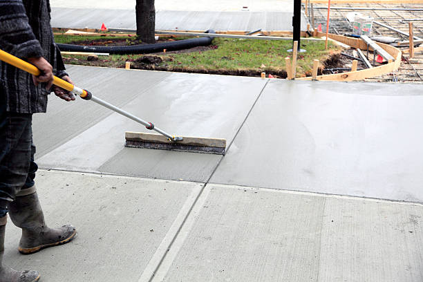 Smoothing And Finishing The New Concrete Driveway Male worker smoothing the just poured concrete driveway. Rebar and framed driveway in background. driveway stock pictures, royalty-free photos & images