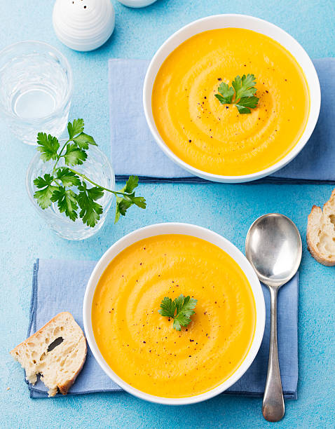 Pumpkin and carrot soup with parsley. Pumpkin and carrot soup with parsley on blue stone background Top view pumpkin soup photos stock pictures, royalty-free photos & images