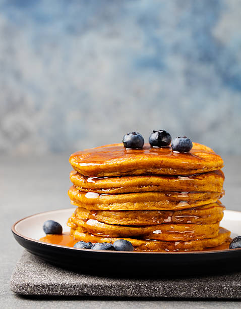 istock Pumpkin pancakes with maple syrup and blueberries on a plate. 612261142