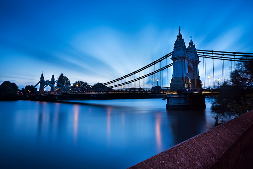 Hammersmith bridge over the Thames river in the evening time. London, UK.