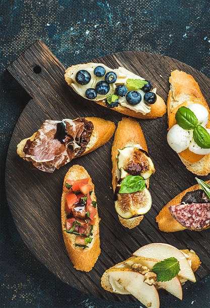 istock Italian crostini with various toppings on round wooden serving board 612261992