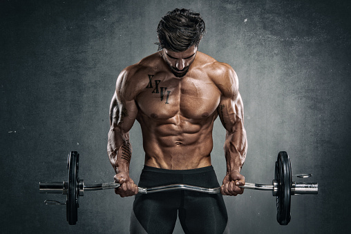 Muscular Men Exercise With Weights. He is performing barbell biceps curls