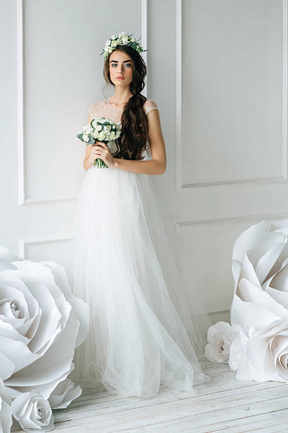 Studio shot of young beautiful bride on background of flowers. Professional make-up and hairstyle.