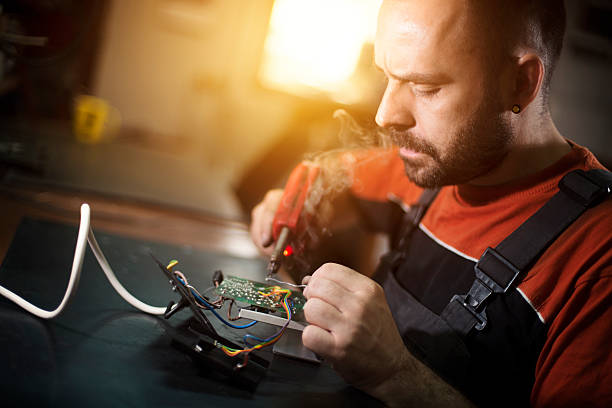 istock Repairman working in workshop and soldering electric board 612264294