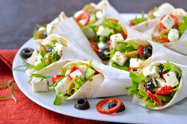 Mini tortillas stuffed with Greek farmers salad with feta cheese and olives, served in wire egg cups