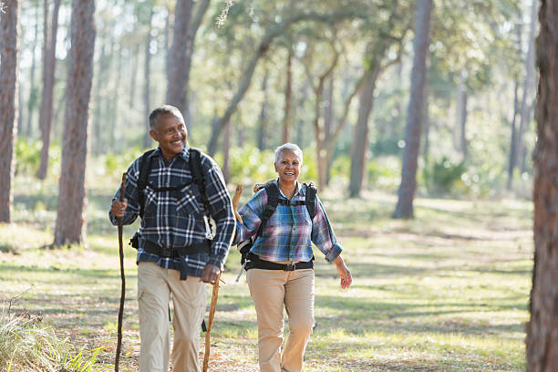 african american seniorzy wędrówki w lesie - senior couple senior adult walking action zdjęcia i obrazy z banku zdjęć