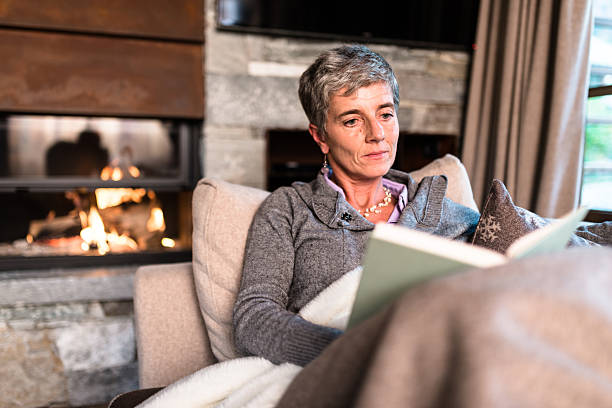 istock woman reading a book on the couch 612269360