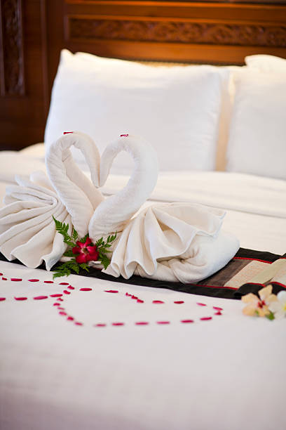 istock Two white towels swans on bed sheet, 612374452