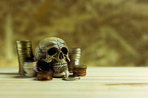 Human skull ,Pile thai coins of one bath on wood background.Concept of financial planning and savings.Vintage tone.