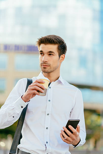 istock Busy man drinking coffee to go and using phone 612385090