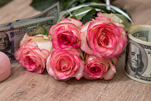 istock beautiful roses with money on desk 612385658