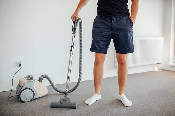 Man is standing and holding vacuum cleaner stock photo