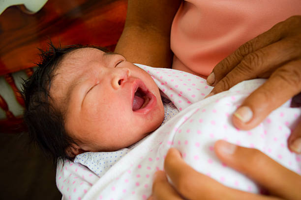 asiatique petit bébé bâille dans un lit - baby yawning asian ethnicity newborn photos et images de collection