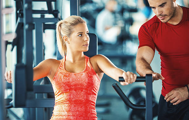 istock Woman exercising in a gym with an instructor. 612388314