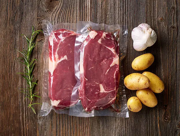 Fresh beef steak for sous vide cooking on wooden table