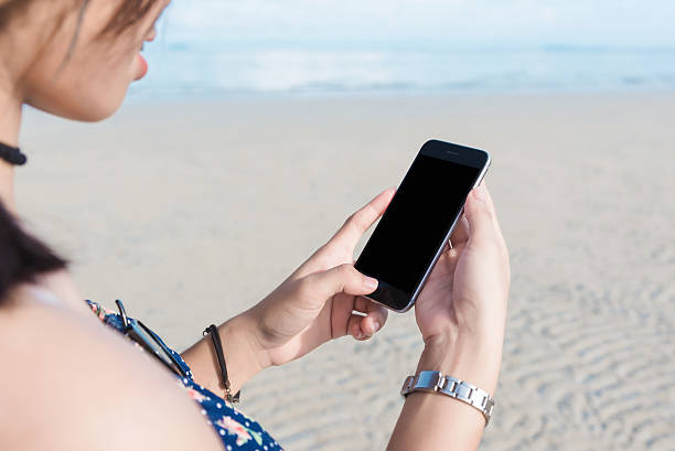 istock Beautiful woman's hand using smart phone at beach 612390906