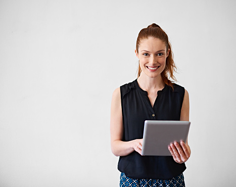 Studio portrait of a young woman using a digital tablet against a gray background