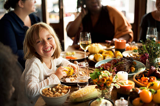 istock Little Girl Eating Corn Thanksgiving Celebration Concept 612394774