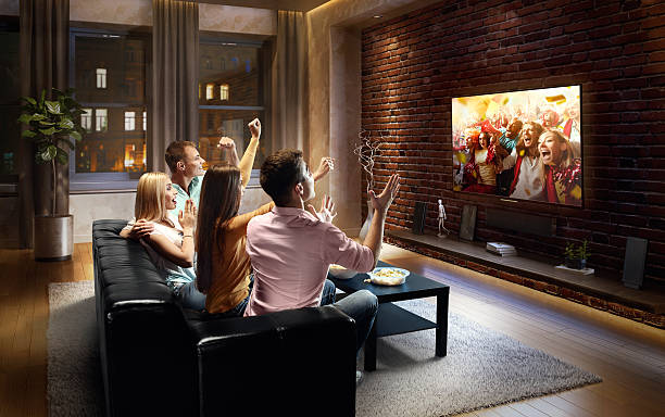 istock Couples cheering and watching sports game on TV 612395520