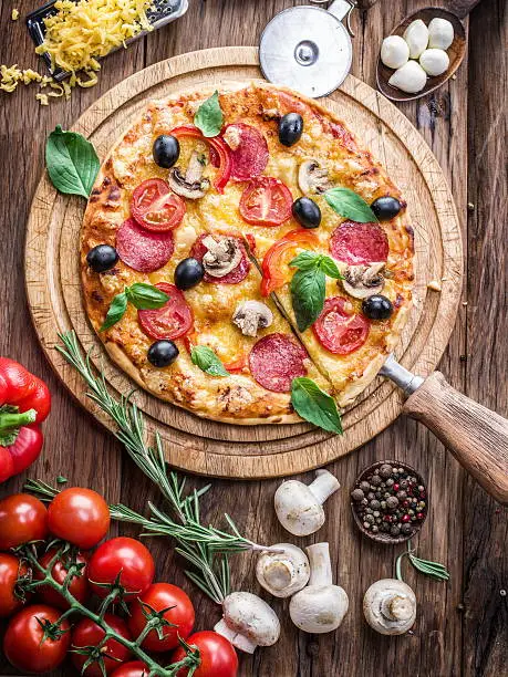 Photo of Pizza with mushrooms, salami and tomatoes.