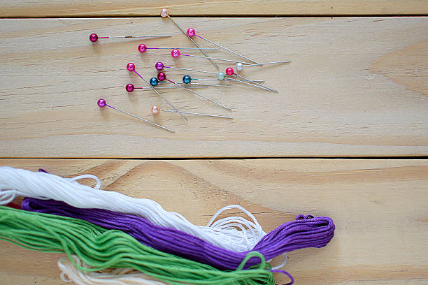 istock sewing pin and threads on wooden background 612396178