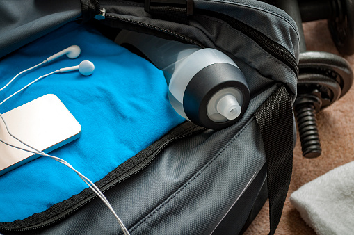 Gym and workout concept with gym bag, water bottle, phone and earbuds