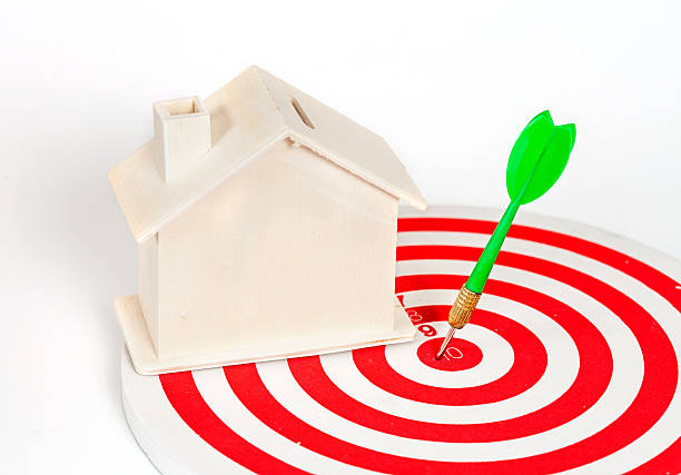istock Miniature house on dart board 612397260