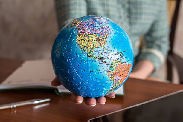 istock Seated at  table woman holding a globe 612398176