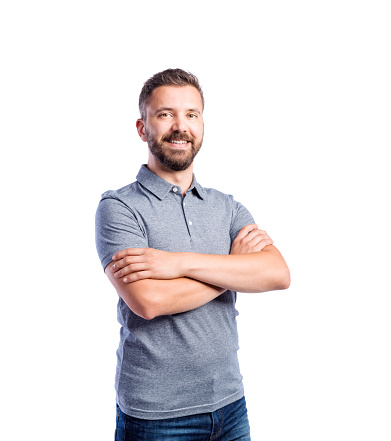 Young handsome hipster man in gray t-shirt, arms crossed, studio shot on white background, isolated
