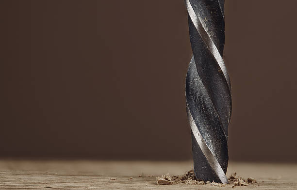 istock Dark old drill bit drilling hole in a wooden plank 612400940
