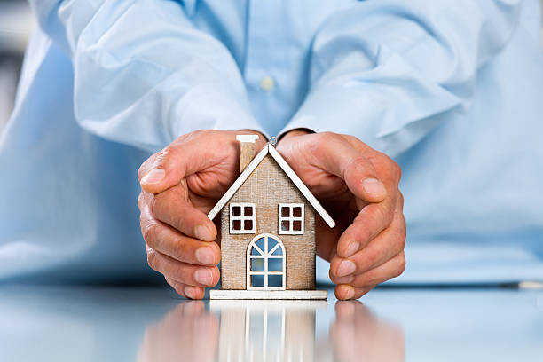 istock Male hands saving Miniature House 612401536