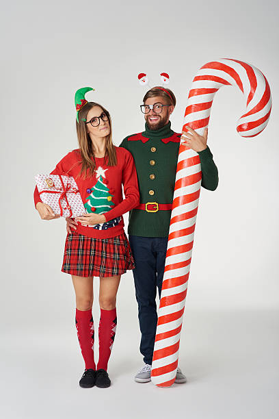 Huge candy cane and Christmas couple Huge candy cane and Christmas couple christmas nerd sweater cardigan stock pictures, royalty-free photos & images
