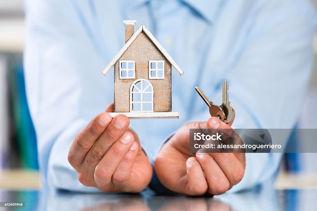 Male Hands holding Miniature House and House Key Male Hands holding Miniature House and House Key. Real Estate Property Concept. Vacation Rental Stock Photo