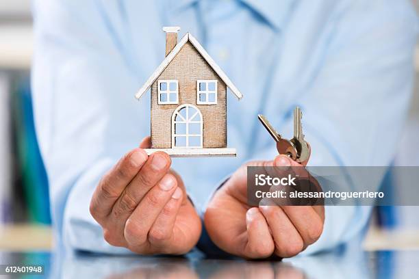 Male Hands Holding Miniature House And House Key Stock Photo - Download Image Now - Vacation Rental, Selling, Deed