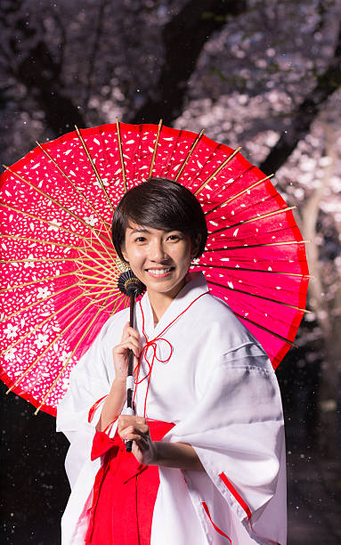 istock Young Miko style woman looking at camera, holding umbrella 612405220