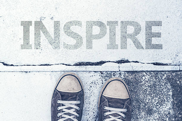 istock Sneakers standing over Inspire title on pavement 612405370
