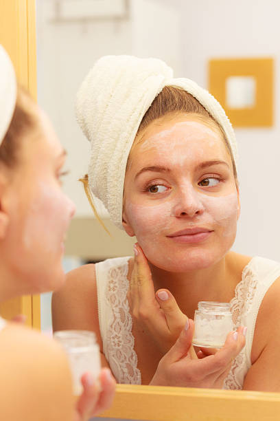 istock Woman applying mask cream on face in bathroom 612408086
