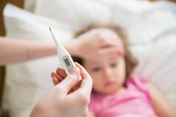 Sick child with high fever Close-up thermometer. Mother measuring temperature of her ill kid. Sick child with high fever laying in bed and mother holding thermometer. Hand on forehead. fever stock pictures, royalty-free photos & images