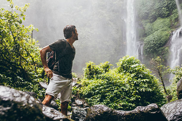 male hiker near waterfall during rain - number of people human gender people waterfall imagens e fotografias de stock