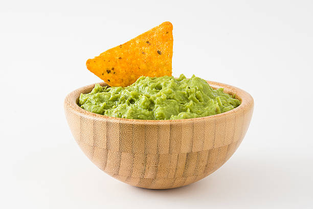Guacamole in a wooden bowl and nacho Guacamole in a wooden bowl and nacho isolated on white background tortilla chip photos stock pictures, royalty-free photos & images