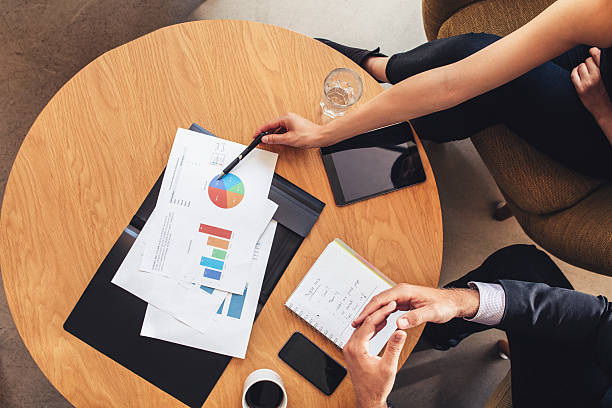 istock Two business people working with charts around table 612413550