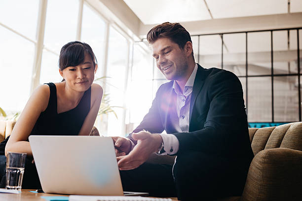 istock two businesspeople using laptop in lobby of modern office 612413720