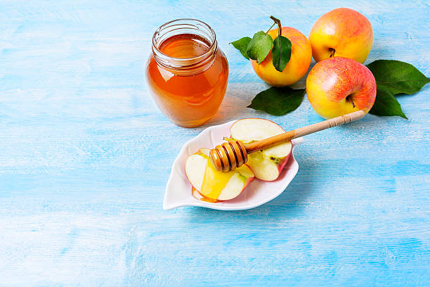 istock Apple slices with honey on blue wooden background 612477692