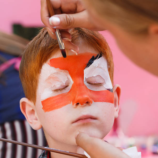 istock Child boy face painting, making tiger eyes process 612479738