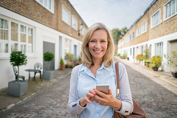 istock Happy woman using her mobile phone on the street 612482210