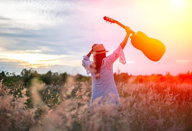 istock Woman happy with guitar in meadow 612484252